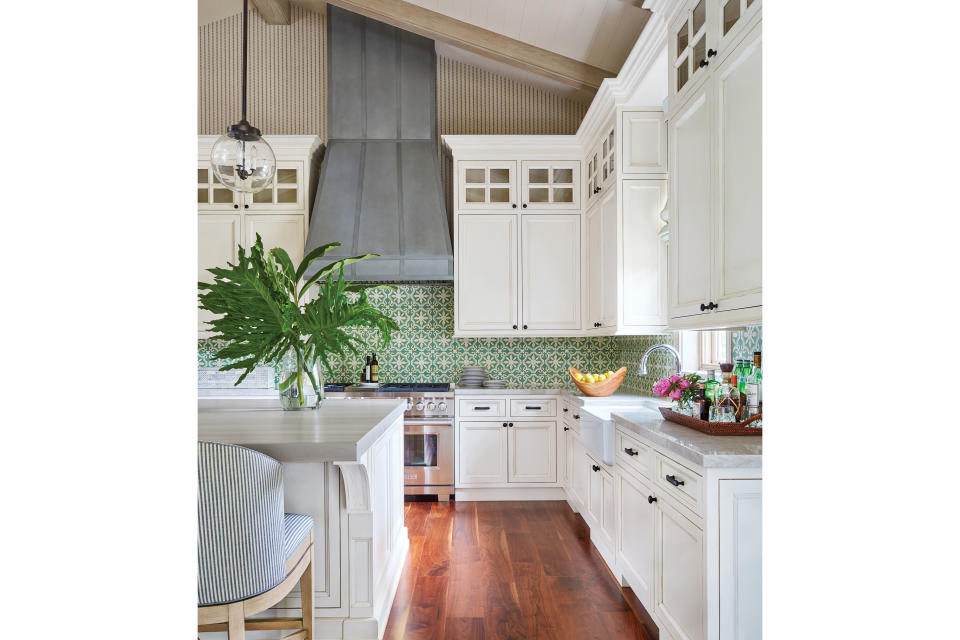 <p>In the kitchen, Sharpe crafted a colorful green backsplash with cement tiles hand-painted in the Dominican Republic. “Everywhere you go on the island, you’re likely to find hand-painted tiles, so these really pull in a great sense of place,” she says. The mahogany butcher block, bleached to match the overhead beams, is paired with stools upholstered in a durable ticking stripe by <a href="https://www.perennialsfabrics.com/" rel="nofollow noopener" target="_blank" data-ylk="slk:Perennials;elm:context_link;itc:0;sec:content-canvas" class="link ">Perennials</a>. Clear globe pendants by <a href="https://urbanelectric.com/" rel="nofollow noopener" target="_blank" data-ylk="slk:The Urban Electric Co.;elm:context_link;itc:0;sec:content-canvas" class="link ">The Urban Electric Co.</a> temper the pretty pattern mix.</p> <p>“We couldn’t have had a sleek white kitchen in this house. It would’ve felt so out of place.” —Ashley Sharpe</p>