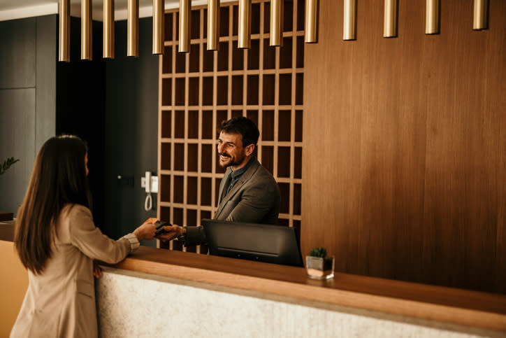 Hotel receptionist handing over a key card to a female guest