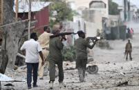 Somali police hold their weapons as they walk outside the Maka Al-Mukarama hotel during an Islamist group al Shabaab attack in the capital Mogadishu, March 27, 2015. REUTERS/Feisal Omar