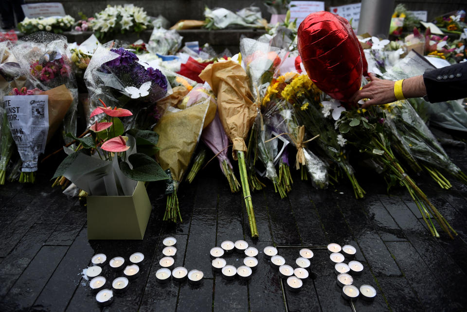 A person lays a floral tribute after a vigil at Potters Field Park.