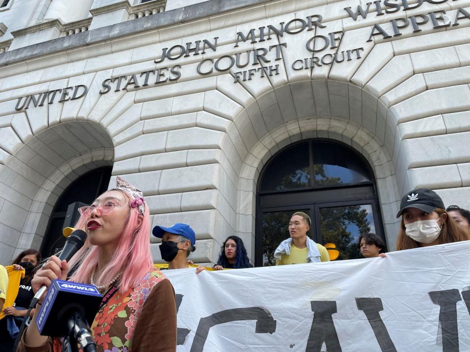 Woojung "Diana" Park, 22, speaks to demonstrators advocating for immigrants outside the 5th U.S. Circuit Court of Appeals building in New Orleans on Wednesday, July 6, 2022. (AP Photo/Kevin McGill)