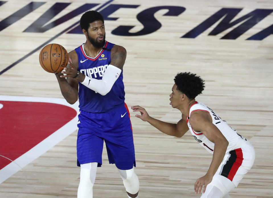 Los Angeles Clippers guard Paul George (13) looks to pass as Portland Trail Blazers guard Anfernee Simons (1) defends during the first half of an NBA basketball game Saturday, Aug. 8, 2020, in Lake Buena Vista, Fla. (Kim Klement/Pool Photo via AP)