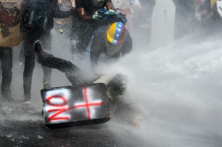 A demonstrator is sprayed by a riot police water cannon during a march against President Nicolas Maduro in Caracas