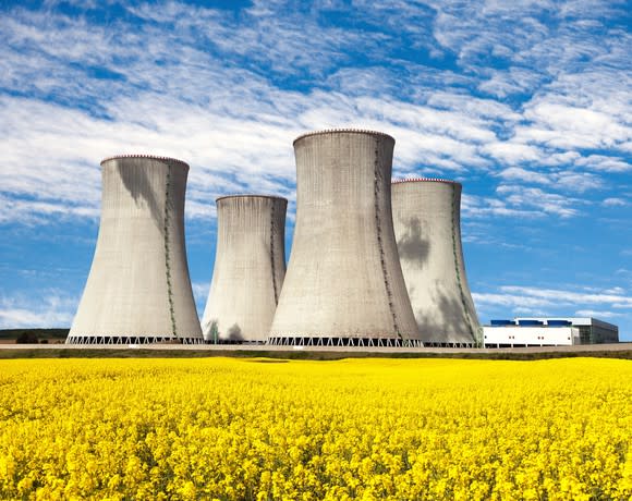 Several nuclear reactors against a yellow field and blue sky backdrop.