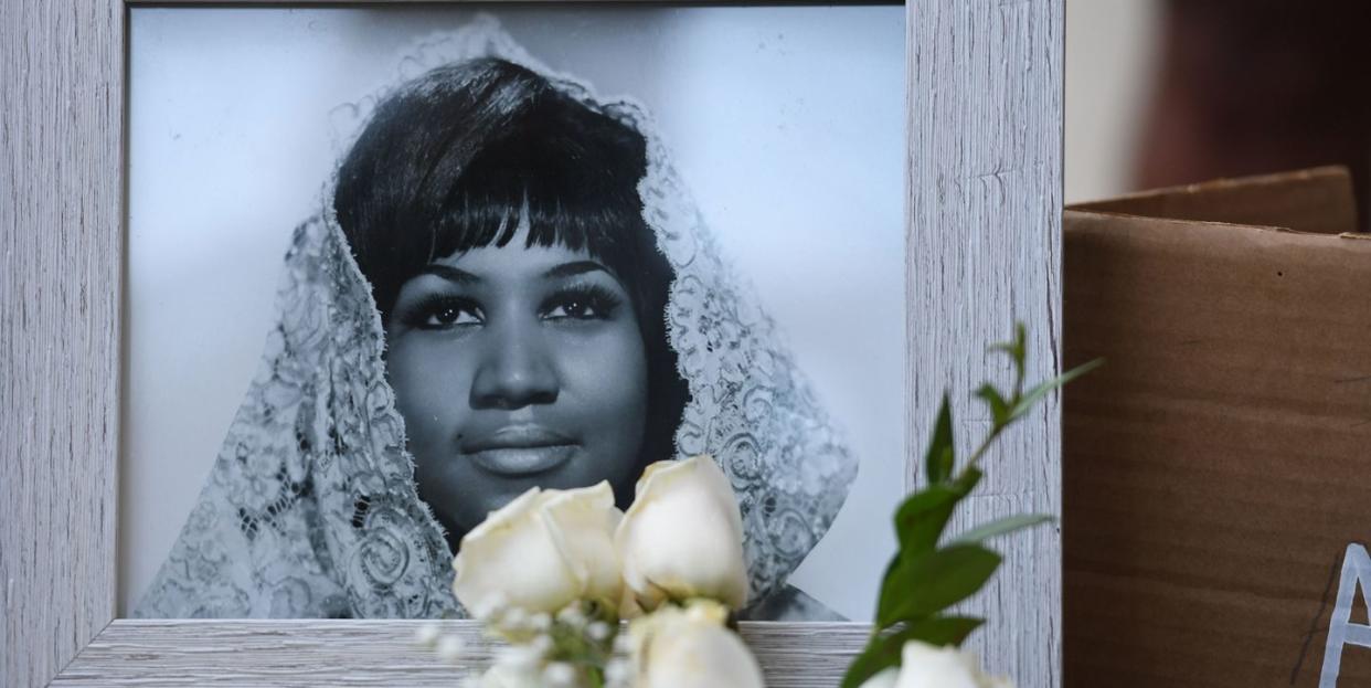 a picture of aretha franklin rets behind a cluster of white flowers