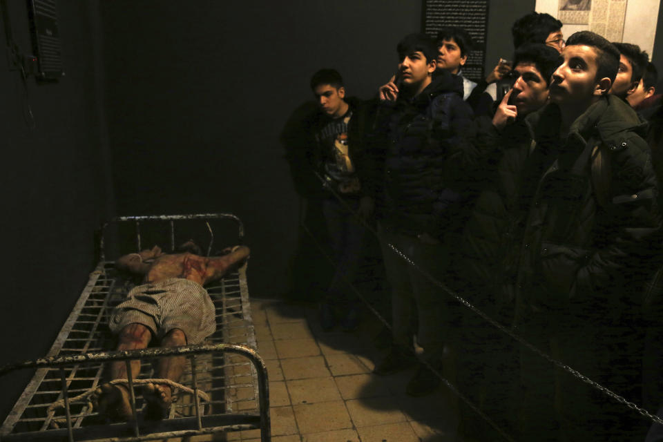 In this Jan. 7, 2019 photo, Iranian schoolboys look at an exhibition at a former prison run by the pre-revolution intelligence service, SAVAK, now a museum, where a wax mannequin of a prisoner is tied to a bed, in downtown Tehran, Iran. As Iran marks the 40th anniversary of its Islamic Revolution and the overthrow of the shah, those who suffered torture at the hands of the police and dreaded SAVAK still bear the scars. U.N. investigators and rights group say that even today, Iran tortures and arbitrarily detains prisoners. (AP Photo/Ebrahim Noroozi)