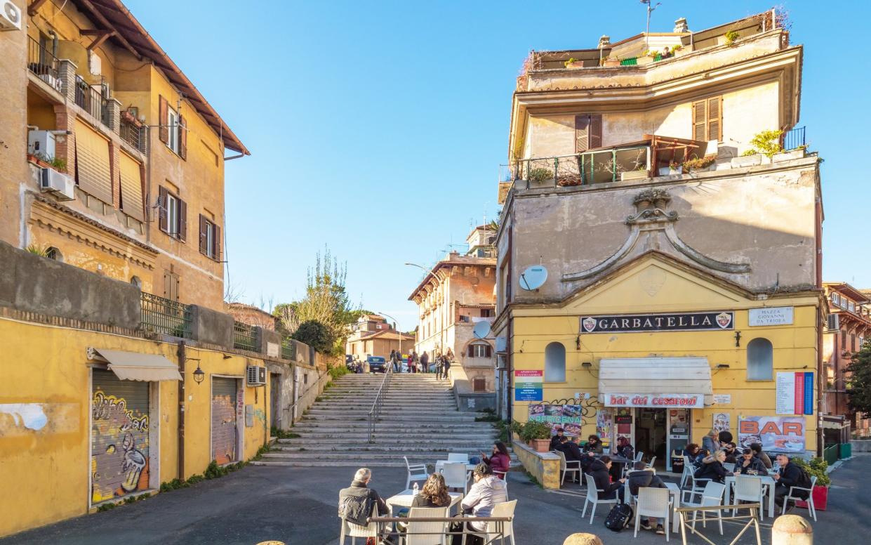 Yellow buildings and people sat on tables outside cafe