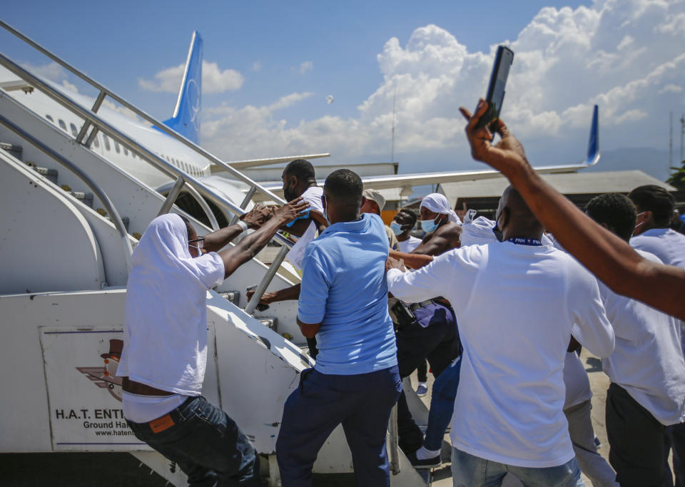 Haitians deported from the United States try to board the same plane in which they were deported, in an attempt to return to the United States, on the tarmac of the Toussaint Louverture airport in Port-au-Prince, Haiti Tuesday, Sept. 21, 2021. (AP Photo/Joseph Odelyn)