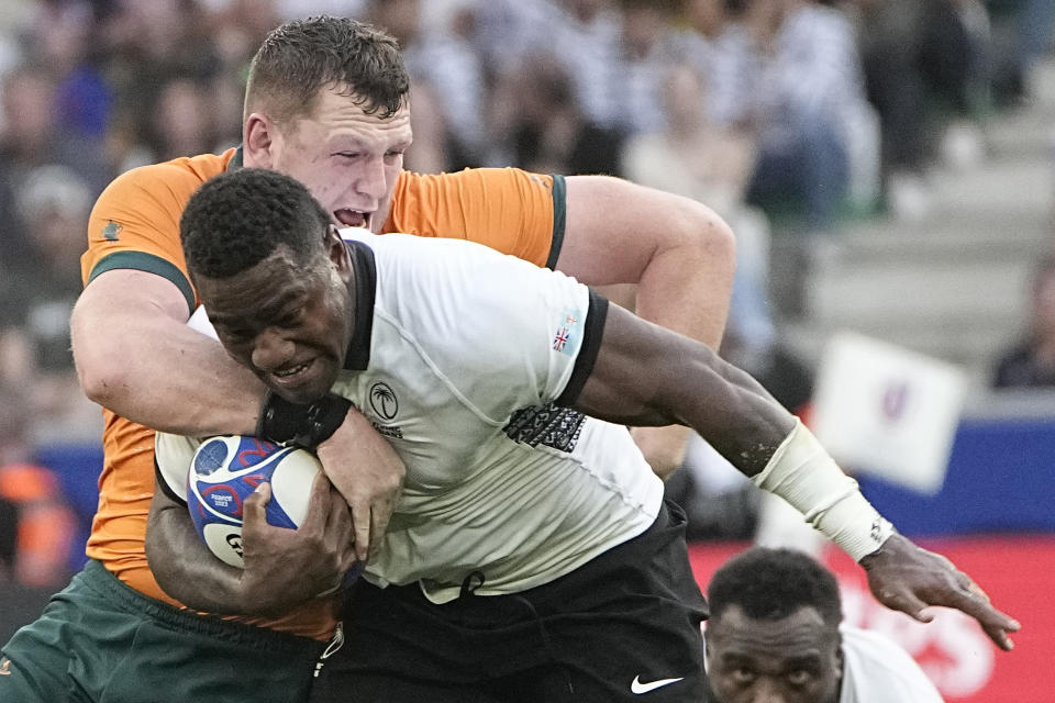 Fiji's Josua Tuisova is tackled by Australia's Angus Bell during the Rugby World Cup Pool C match between Australia and Fiji at the Stade Geoffroy Guichard in Saint-Etienne, France, Sunday, Sept. 17, 2023. (AP Photo/Laurent Cipriani)