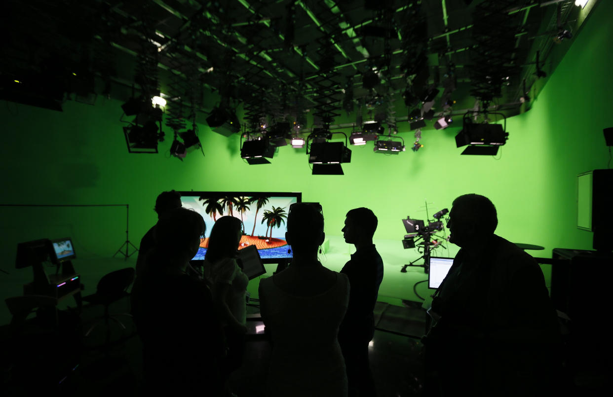 FILE - In this Tuesday, June 11, 2013, photo, employees of the "Russia Today" television channel prepare for a visit by Russian President Vladimir Putin to Russia Today's new headquarters in Moscow, Russia. Russia-backed RT television network's move to establish in July 2022 a news bureau in South Africa has been described as part of that government's long-term attempts to grow its influence in Africa. (Yuri Kochetkov/Pool Photo via AP, File)