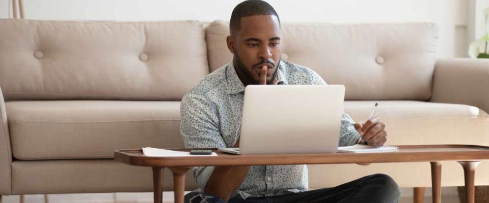Focused young african american man studying or working on laptop, shopping for a low mortgage rate