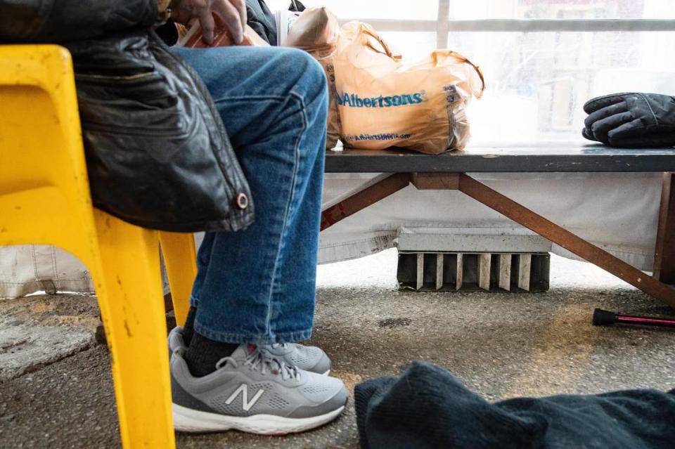 A homeless man eats lunch next to heater inside of a large tent on the Interfaith Sanctuary property on Tuesday.