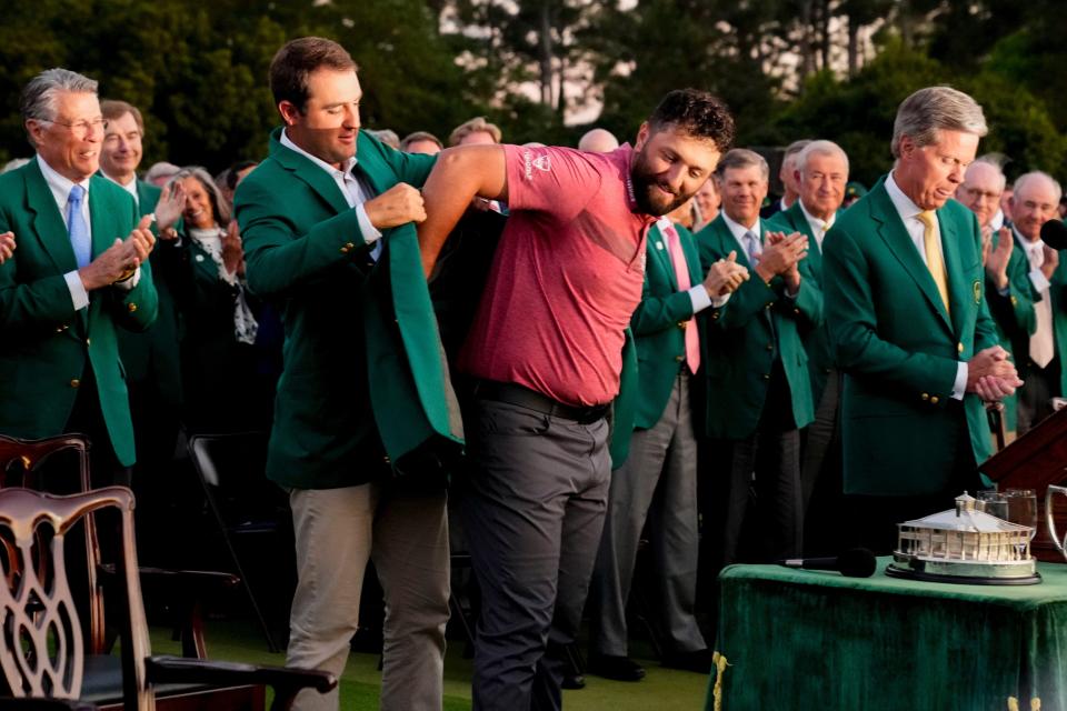 2022 Masters champion Scottie Scheffler helps Jon Rahm into his green jacket after the final round of The Masters golf tournament on Apr 9, 2023.