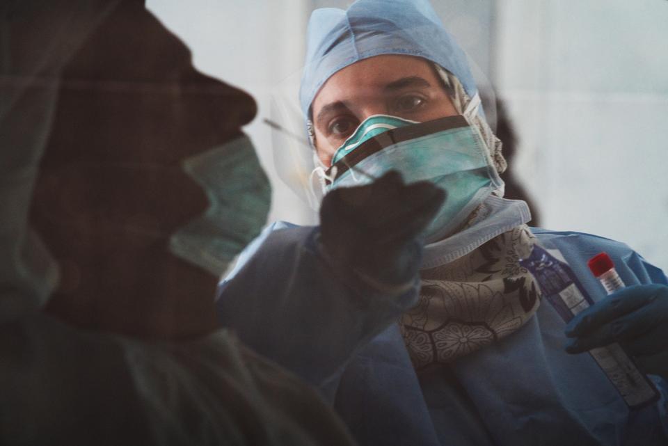 FILE - In this April 2, 2020, file photo taken through a tinted car window, a technician takes a nasal swab for a coronavirus detection test at a drive-thru testing facility in Abu Dhabi, United Arab Emirates. The United Arab Emirates said Wednesday, Dec. 9, 2020, that a Chinese coronavirus vaccine by Sinopharm tested in the federation of sheikhdoms is 86% effective, though it released few details. (AP Photo/Jon Gambrell, File)