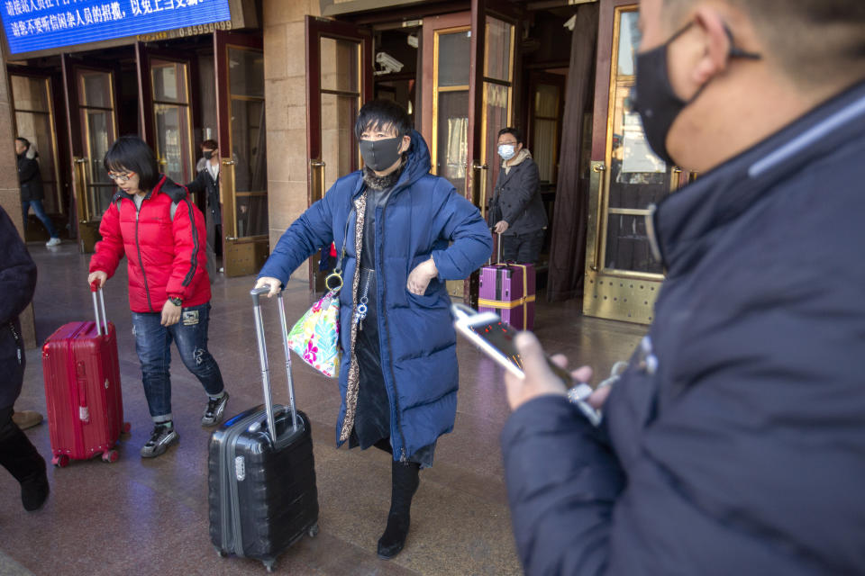 Travelers wear face masks as they walk outside of the Beijing Railway Station in Beijing, Monday, Jan. 20, 2020. China reported Monday a sharp rise in the number of people infected with a new coronavirus, including the first cases in the capital. The outbreak coincides with the country's busiest travel period, as millions board trains and planes for the Lunar New Year holidays. (AP Photo/Mark Schiefelbein)