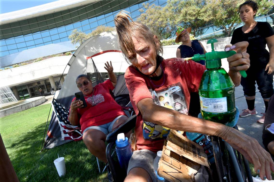 58-year-old Shelley Forest, who is homeless and has health issues, uses what she says is the key to survival for her and others on the streets who endure the brutal summer heat in Fresno- a spray bottle of water, as she and others like her and homeless advocates set up camp on the lawn of City Hall, demanding shelter from city leaders, July 20, 2021.
