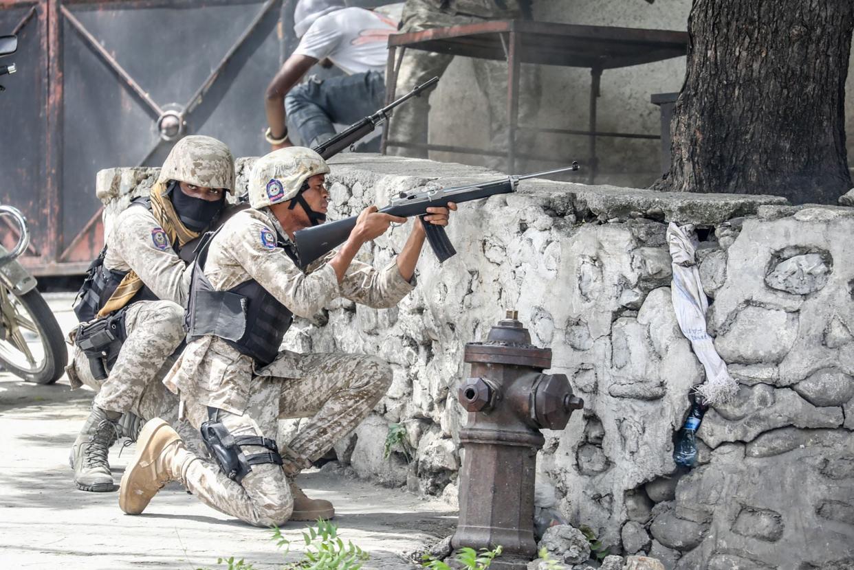 Security forces member exchange gunfire with armed men next to the Petionville police station in Port-au-Prince  (AFP via Getty Images)