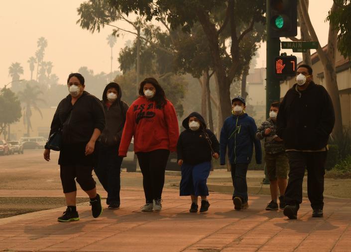 <p>A family wears face masks as they walk through the smoke filled streets after the Thomas wildfire swept through Ventura, California on Dec. 6, 2017. (Photo: Mark Ralston/AFP/Getty Images) </p>