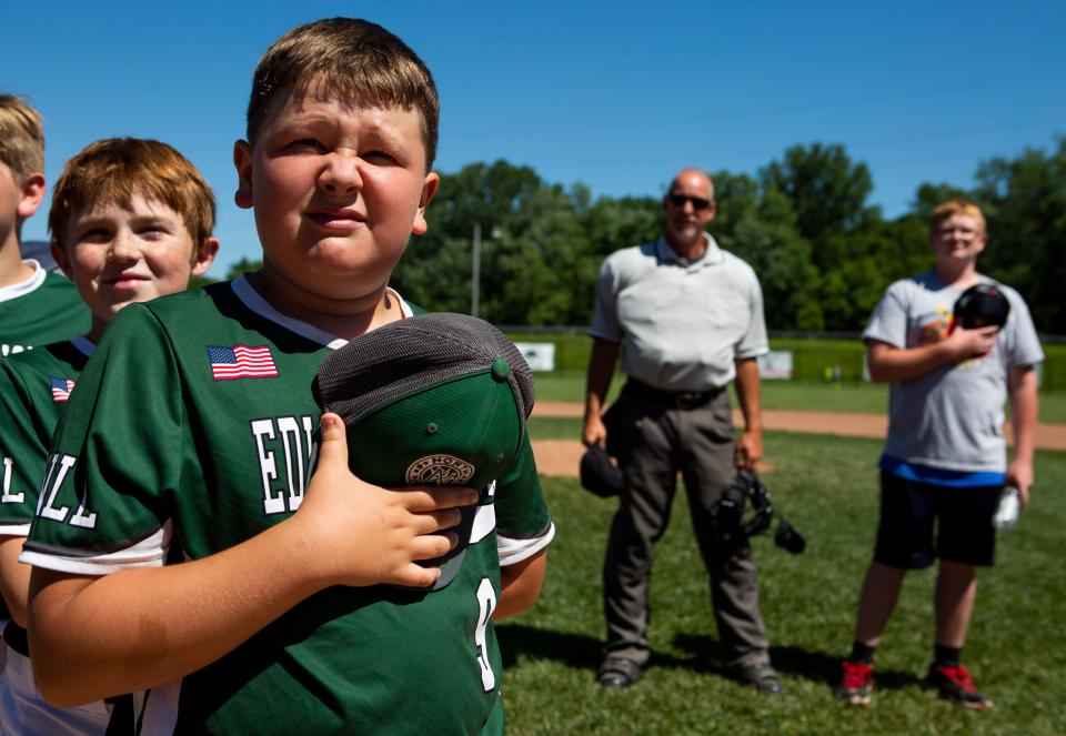 Edward Jones' Lleyton Rector holds his hat over his heart as the National Anthem plays before the start of their game against Central Ohio Garage Door Mariners during the Shrine Baseball Tournament Quarterfinals at Mound City Little League in Newark, Ohio on June 18, 2022.