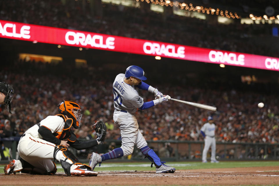 Los Angeles Dodgers' Mookie Betts hits a single in front of San Francisco Giants catcher Buster Posey during the fourth inning of Game 5 of a baseball National League Division Series Thursday, Oct. 14, 2021, in San Francisco. (AP Photo/Jed Jacobsohn)