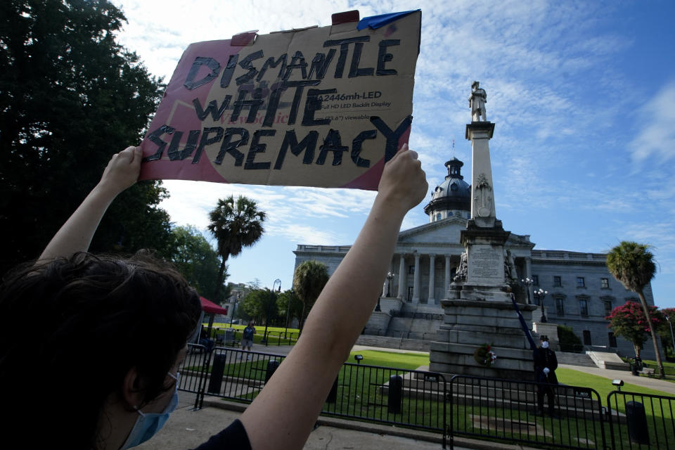 A demonstrator protests in front of a civil war statue at the State House on Friday, July 10, 2020, in Columbia, S.C. Demonstrators on both sides gathered for the five year anniversary after the Confederate battle flag was removed from the State House grounds after a two-thirds vote by the Legislature. (AP Photo/Chris Carlson)