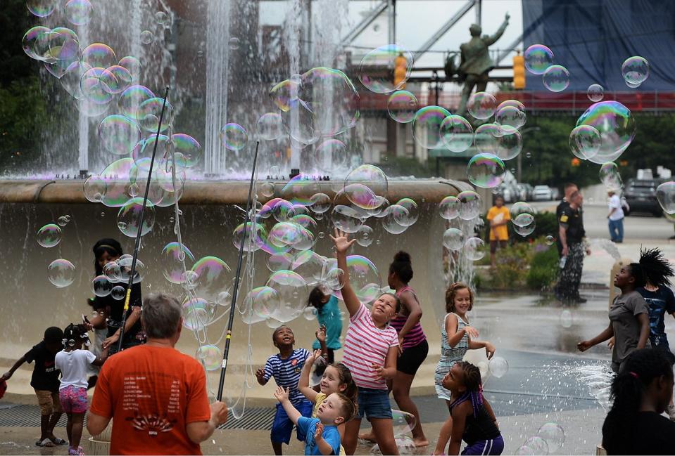 Children reach for bubbles created by Lee Sedgwick, lower left, in Perry Square during CelebrateErie in 2018.