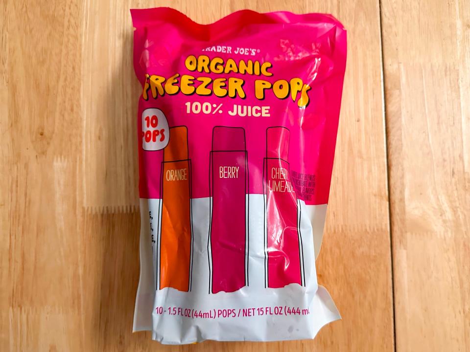 A pink and white bag with illustration of red, pink, and orange ice pops sitting on a wooden table