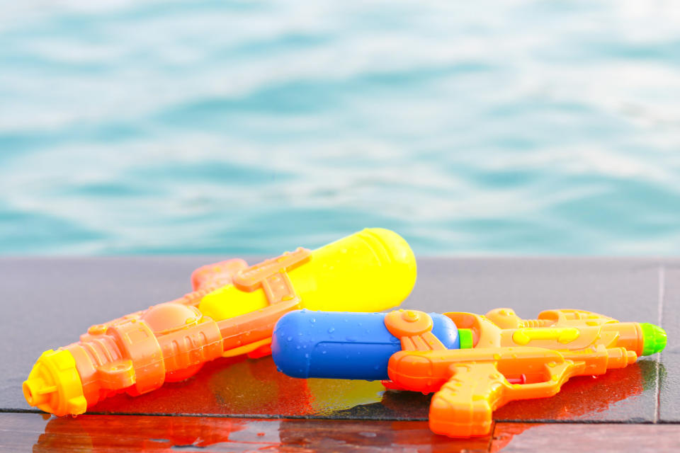 Colorful kids' water guns near a pool