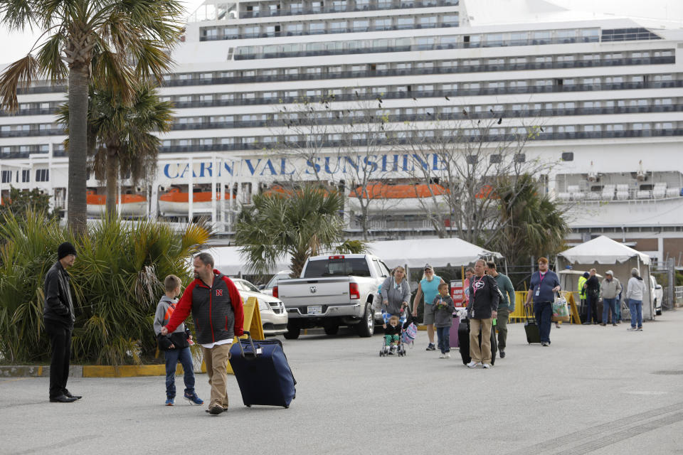 Passengers disembark from the Carnival Sunshine cruise ship Monday, March 16, 2020, in Charleston, S.C. Passengers said they had their temperature taken before getting on the cruise ship for the four-day cruise to the Bahamas but did not have their temperature taken getting off. According to passengers, cruise officials did ask them if they felt okay when leaving. (AP Photo/Mic Smith)