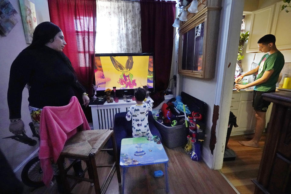 Isabel Miranda, left, speaks to her 4-year-old son, Julian, while her other son, Jayden, 13, prepares hot chocolate in the kitchen, Wednesday, March 10, 2021, of their rental apartment in Haverhill, Mass. The Biden administration is extending a federal moratorium on evictions of tenants who've fallen behind on rent during the coronavirus pandemic. Miranda, who has an eviction hearing next month from her apartment, said she had mixed feelings about the extension. She worries that the courts and the landlord will not recognize the federal moratorium but also recognizes it gives her time to come up with the nearly $10,000 in back rent. (AP Photo/Elise Amendola)