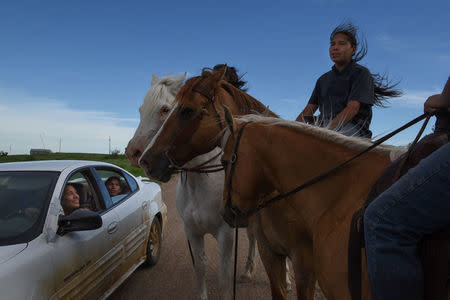 Angel Lookinghorse stops her car next to her brother, Jayden Lookinghorse riding his horse, on the Cheyenne River Reservation in Green Grass, South Dakota, U.S., May 30, 2018. REUTERS/Stephanie Keith