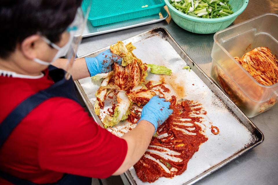 Kimchi Plus owner Young Hi Kim adds sok to napa cabbage to make kimchi.