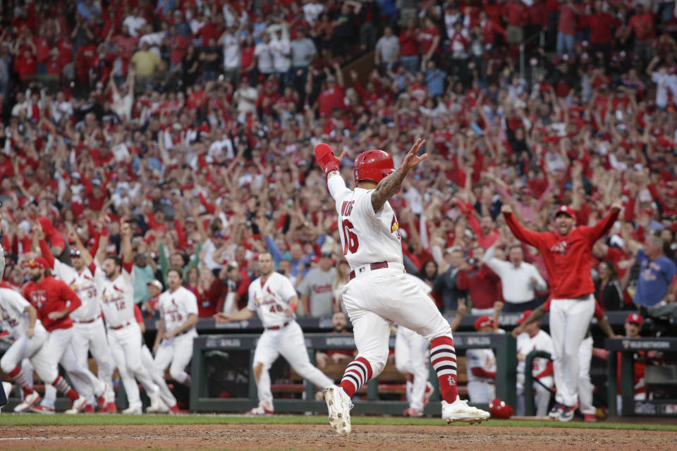 El jugador de los Cardenales de San Luis, Kolten Wong (16), anota la carrera ganadora en un elevado de sacrificio del puertorriqueño Yadier Molina, durante el 10mo inning del cuarto juego de la Serie Divisional de la Liga Nacional contra los Bravos de Atlanta, el lunes 7 de octubre de 2019, en San Luis. (AP Foto, Charlie Riedel)