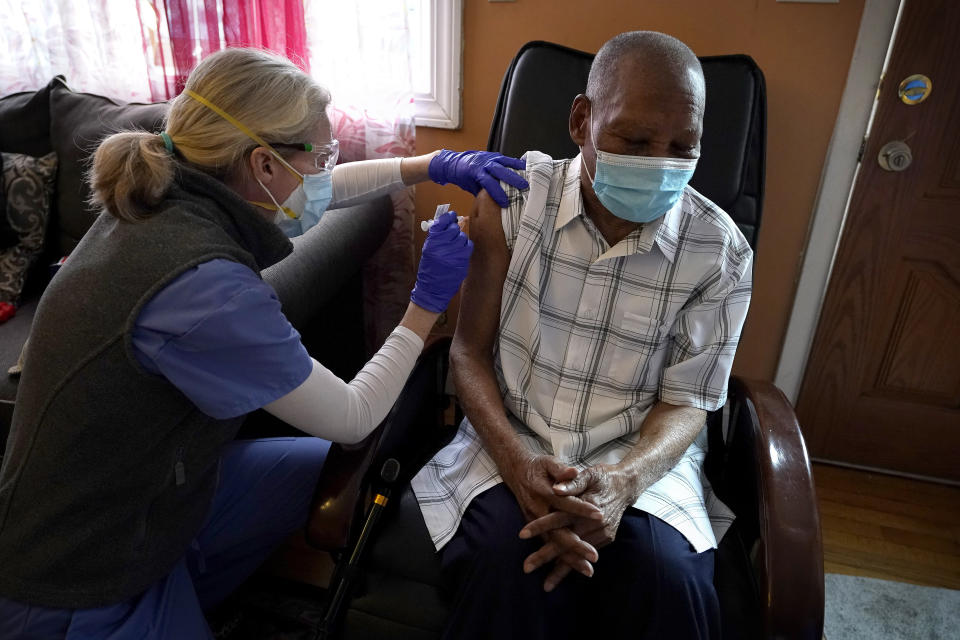 Geriatrician Megan Young, left, gives Edouard Joseph, 91, a COVID-19 vaccination Thursday, Feb. 11, 2021, at his home in the Mattapan neighborhood of Boston. Millions of U.S. residents will need COVID-19 vaccines brought to them because they rarely or never leave home. Doctors and nurses who specialize in home care are leading this push and starting to get help from state and local governments around the country. (AP Photo/Steven Senne)