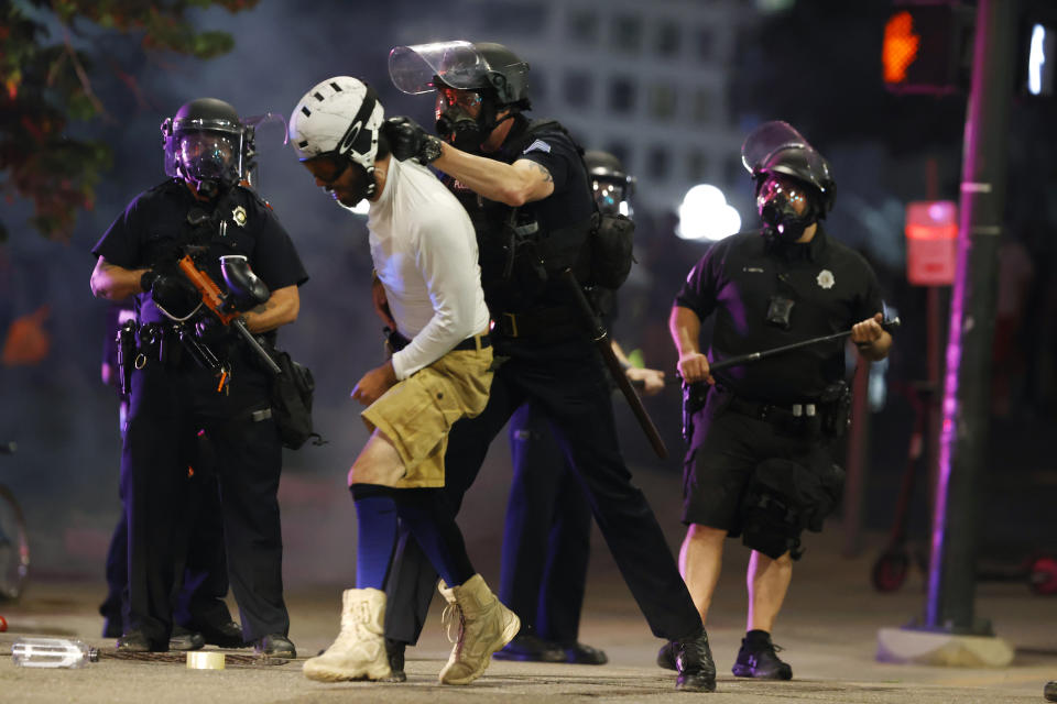 Denver Police Department officers clear a man who fell to the street after they used tear gas and rubber bullets to disperse a protest outside the State Capitol over the death of George Floyd, a handcuffed black man who died in police custody in Minneapolis, late Thursday, May 28, 2020, in Denver. (AP Photo/David Zalubowski)