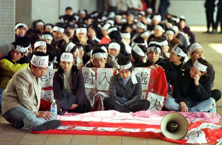 More than 100 mainland Chinese visitors wearing headbands protest outside Hong Kong's Legal Aid Department to demand immediate residency in the territory, February 8, 1999. In 1999, the hopes of many aspiring cross-border families were dashed when Beijing, at the Hong Kong government's request, overturned a ruling by Hong Kong's top court that granted broad residency rights. "I will never forget this, nor forgive the government for what it did," Ho Hei-wah, a veteran family activist, said later. "It split many families and meant they couldn't live together." REUTERS/Bobby Yip/File photo