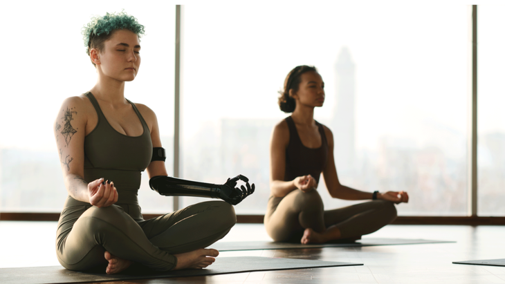 College students sitting cross-legged on yoga mats meditating