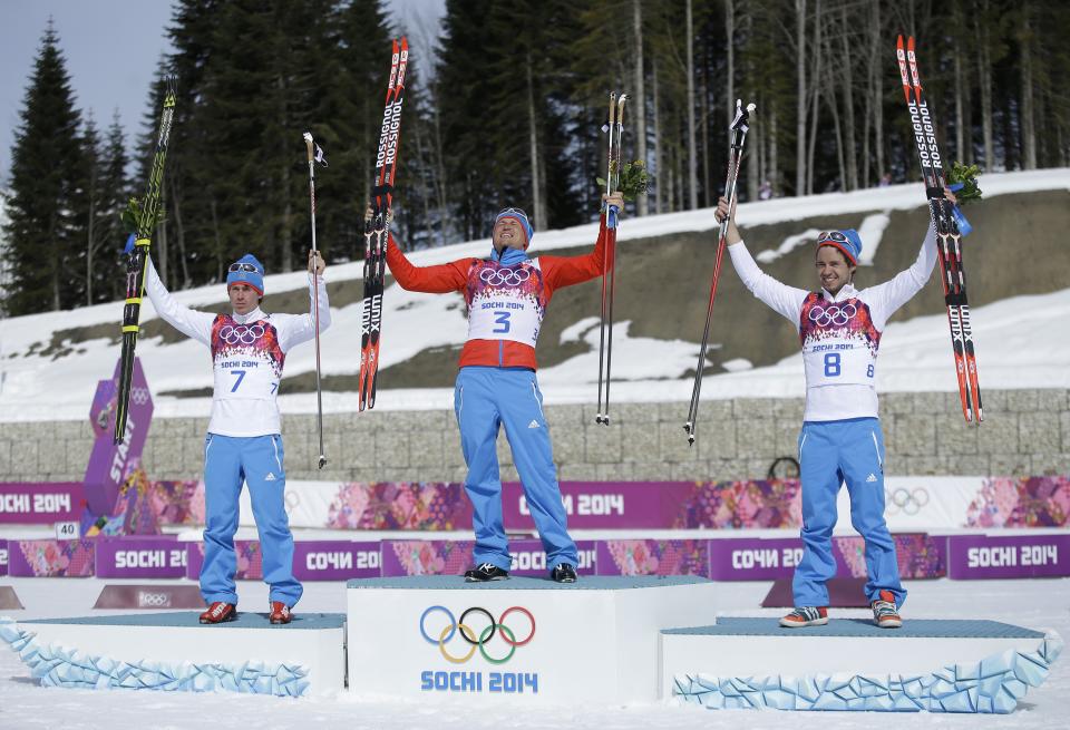 Russia's gold medal winner Alexander Legkov is flanked by Russia's silver medal winner Maxim Vylegzhanin, left and Russia's bronze medal winner Ilia Chernousov during the flower ceremony of the men's 50K cross-country race at the 2014 Winter Olympics, Sunday, Feb. 23, 2014, in Krasnaya Polyana, Russia. (AP Photo/Gregorio Borgia)