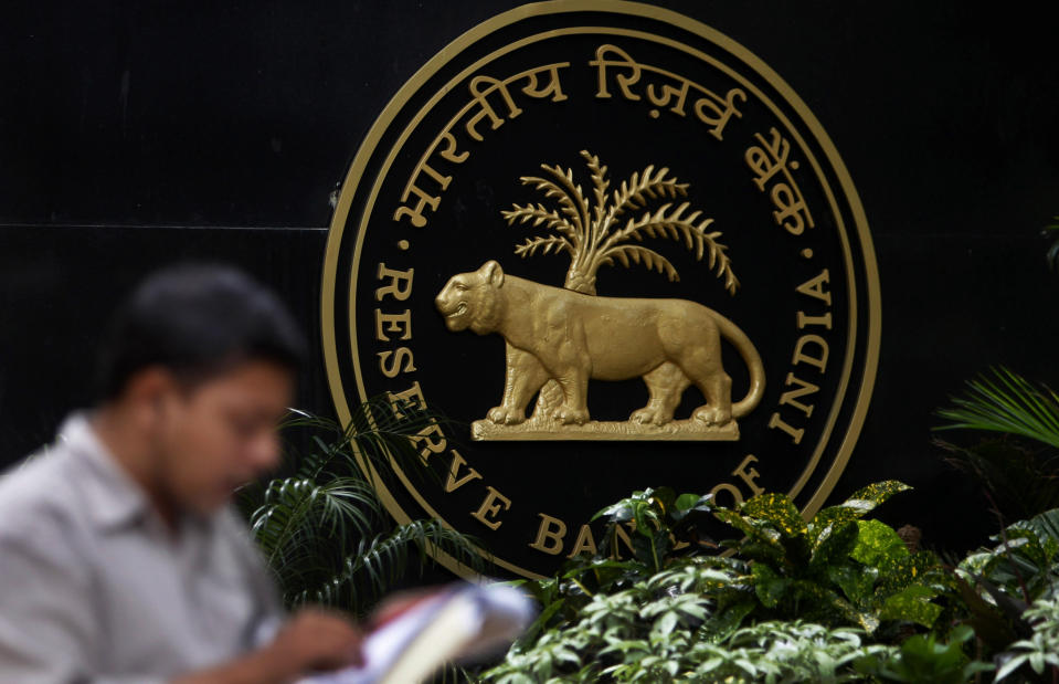 A media person speaks on phone next to the logo of the Reserve Bank of India (RBI) in Mumbai, India, Tuesday, April 17, 2012. The RBI slashed India's key interest rate by half a percentage point Tuesday, the first cut in three years and more than economists had expected. (AP Photo/Rafiq Maqbool)