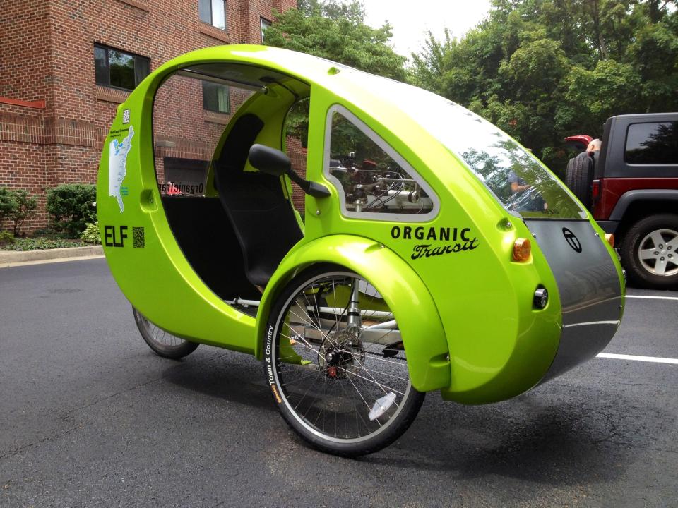 This photo taken July 24, 2013 shows the Organic Transit’s ELF bike in a parking lot in Reston, Va. It’s the closest thing yet to Fred Flintstone’s footmobile _ only with solar panels and a futuristic shape. It’s an “Organic Transit Vehicle,” a car-bicycle blend also known as an ELF bike, and 65-year-old family therapist Mark Stewart is taking it on a 1,200-mile journey along the East Coast Greenway, a bike and pedestrian trail that runs from Florida to Canada. (AP Photo/Valerie Bonk)