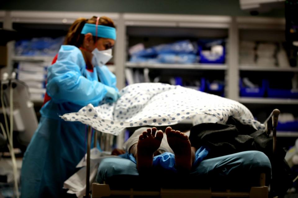 A nurse places a blanket over an ER patient.