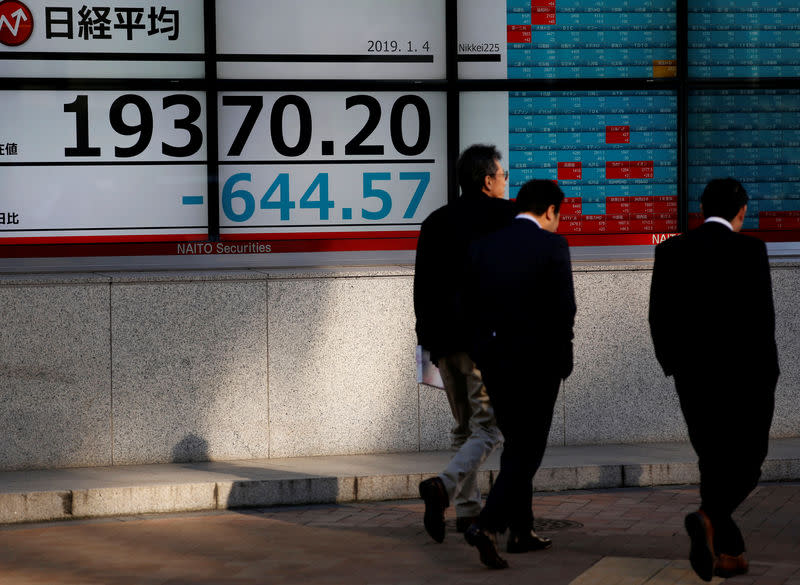 Men walk past an electronic board showing Nikkei average outside a brokerage in Tokyo, Japan, January 4, 2019. REUTERS/Kim Kyung-Hoon