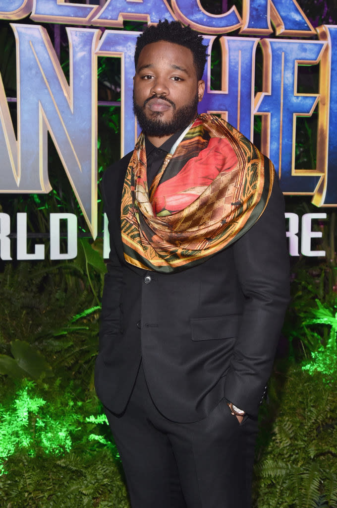 Ryan with a suit, a colorful scarf, and hands in his pants pockets at the Los Angeles world premiere of "Black Panther"
