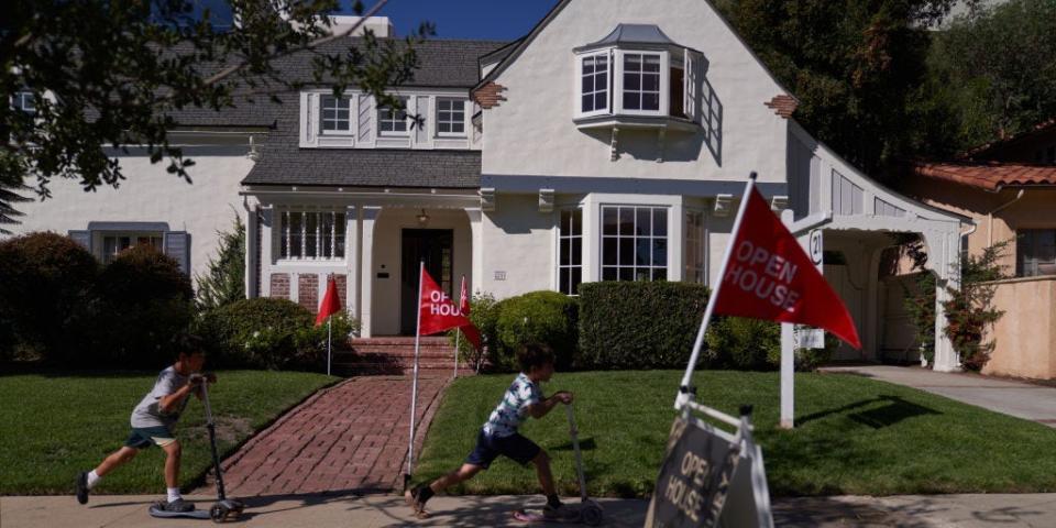 Children ride scooters past 'open house' flags displayed outside a single family home in Los Angeles, California.