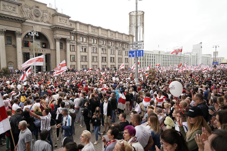 Belarusian opposition supporters rally with old Belarusian national flags rally toward Independence Square in Minsk, Belarus, Sunday, Aug. 23, 2020. A vast demonstration with many thousands of protesters demanding the resignation of Belarus' authoritarian president are rallying in the capital, continuing the public dissent since the disputed presidential election. (AP Photo/Evgeniy Maloletka)