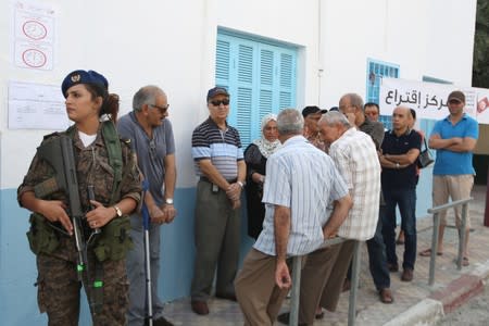 A soldier stands guard as people queue to cast their vote at a polling station during presidential election in Sousse