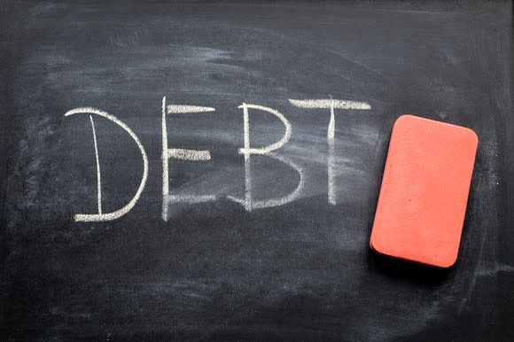 The word debt is written on a blackboard with an eraser nearby.