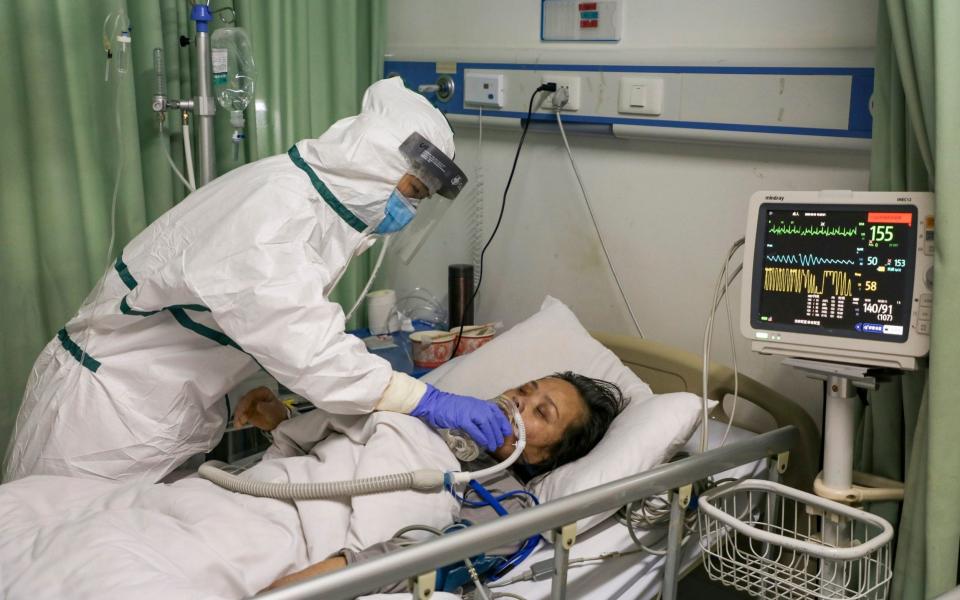 A nurse feeds water to a patient in the isolation ward for coronavirus patients at a hospital in Wuhan - CHINATOPIX/AP