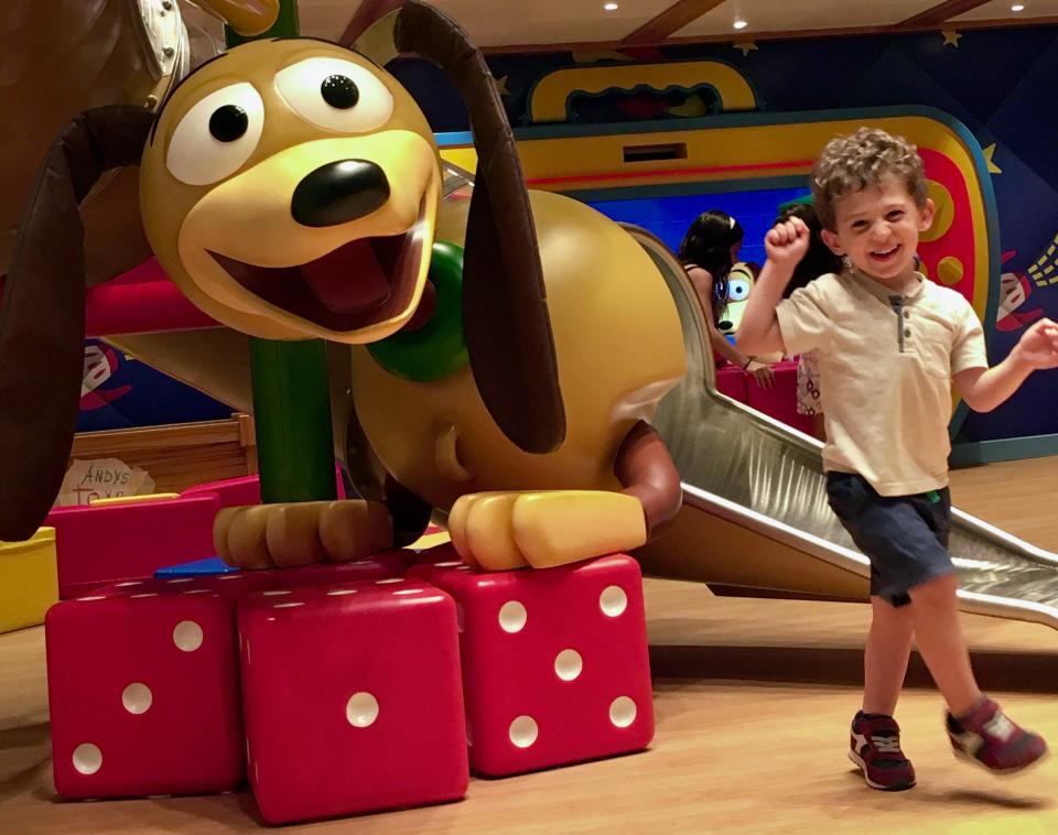 The author's son smiling as a toddler at a Toy Story-themed kids club on a Disney cruise