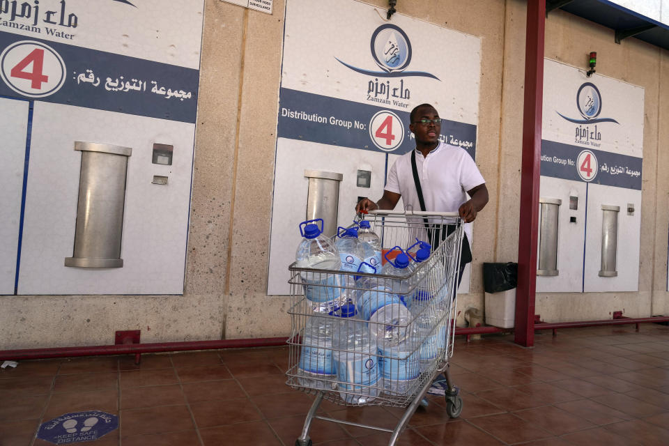 A man pushes a trolly full of Zamzam water bottles, drawn from the well beneath the Grand Mosque in Mecca, at Zamzam bottle point in Mecca, Saudi Arabia, Thursday, June 22, 2023. Muslim pilgrims are converging on Saudi Arabia's holy city of Mecca for the largest hajj since the coronavirus pandemic severely curtailed access to one of Islam's five pillars. (AP Photo/Amr Nabil)